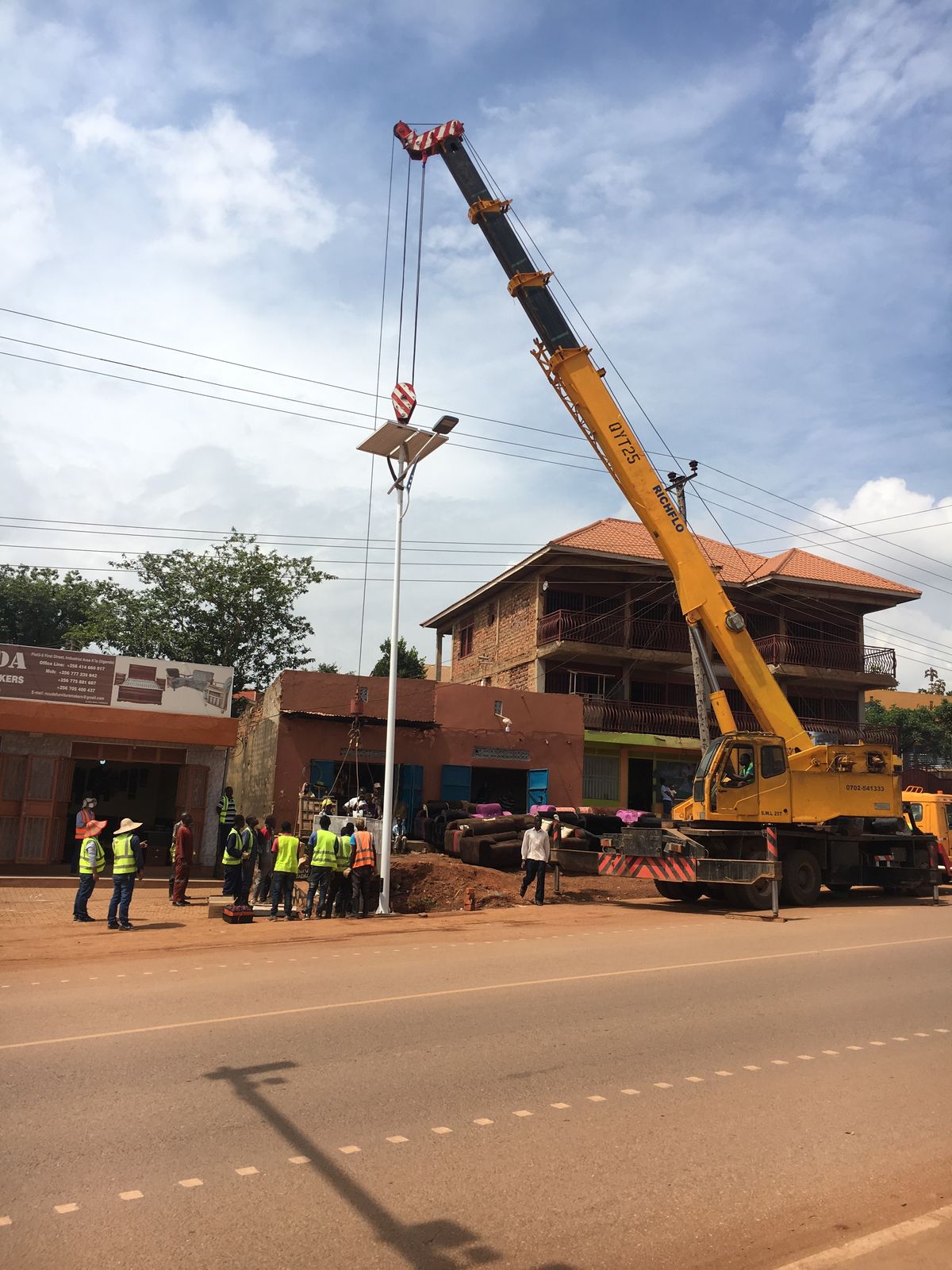 Crane lifting the pole, panel and luminaire into position